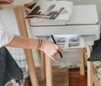 Woman printing photos on paper while forking at home