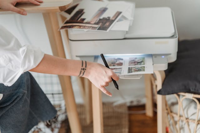 Woman printing photos on paper while forking at home