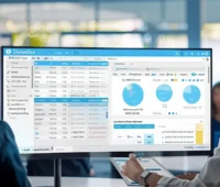 A man and woman in business attire analyze a computer screen displaying the SalesForce opportunity tool.