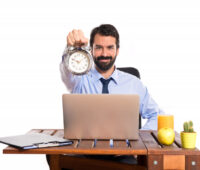 man in his office holding a clock