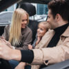 man sitting in car with his wife and daughter