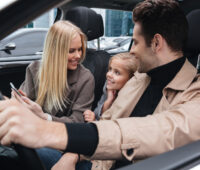 man sitting in car with his wife and daughter