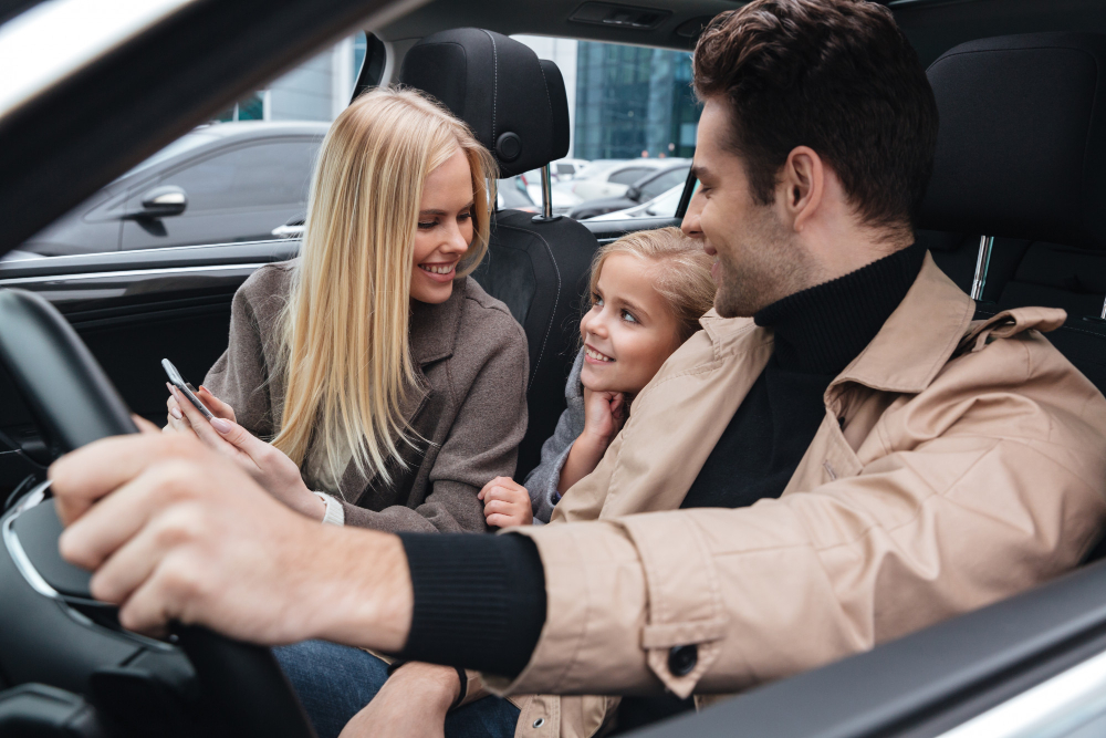 man sitting in car with his wife and daughter