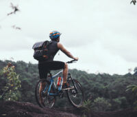 man with bicycle standing on mountain against sky