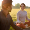 Smiley woman and man meditating outdoors on yoga mat