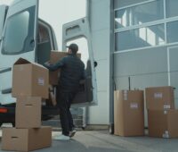 Man in Blue Jacket and Blue Denim Jeans Sitting on Brown Cardboard Box