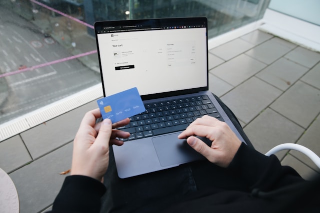 Holding a credit card while finalizing an online purchase, showcasing SumUp’s seamless integration for secure payments.