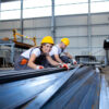 Industrial workers working in factory hall with metal