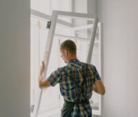 workman installing window in house during renovation process