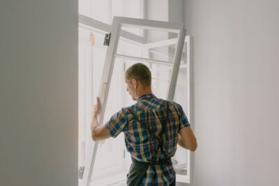 workman installing window in house during renovation process