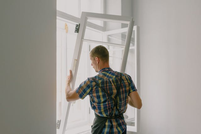 workman installing window in house during renovation process