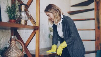 Professional housekeeper is dusting furniture with wet cloth