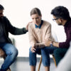 Young sad woman being consoled during group counselling