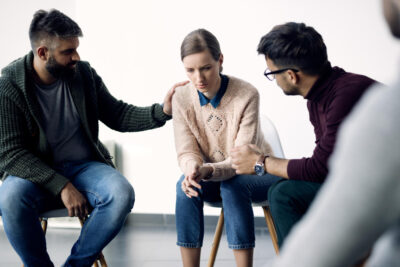 Young sad woman being consoled during group counselling