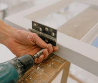 Crop workman drilling hinge on window frame