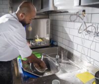 A Man Washing the Frying Pan on the Sink