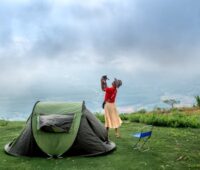 Woman Standing near a Tent Holding Her Pet Dog
