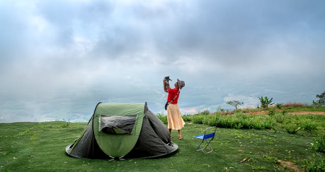 Woman Standing near a Tent Holding Her Pet Dog