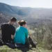 Couple sitting on mountain against clear sky