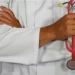 doctor stands holding a stethoscope in his right hand