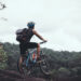 man with bicycle standing on mountain against sky