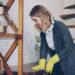 Professional housekeeper is dusting furniture with wet cloth
