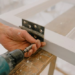 Crop workman drilling hinge on window frame