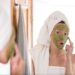 The woman applies green organic face mask in the bathroom